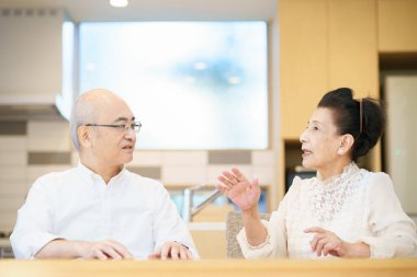 Yaşlı çift oturma odasında gülücükle sohbet ediyor.