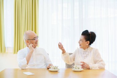 Üst düzey bir çift parlak bir oturma odasında sohbet ediyor.