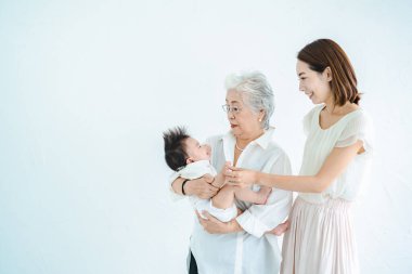 Yaşlı kadınlar bebeklere sarılıyor ve kadınlar izliyor.