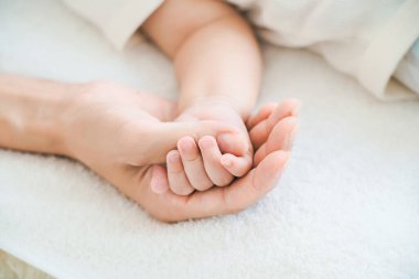 Annenin eli bebeğinin elini tutuyor.