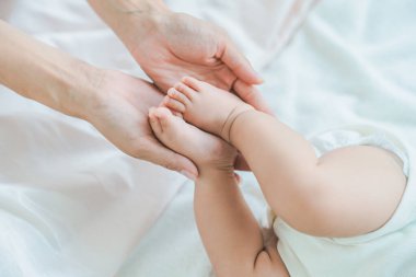 Annenin elleri odada bebeğin ayaklarını destekliyor.