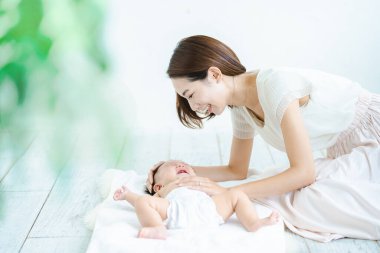 Asyalı anne ve bebek içeride oynuyorlar.