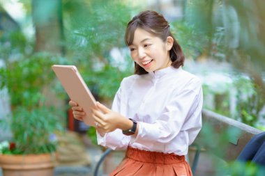 Yeşil boşlukta tablet bilgisayar kullanan bir kadın