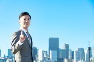 İşadamı güzel bir günde işaret parmağıyla poz verir.