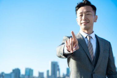 İşadamı güzel bir günde işaret parmağıyla poz verir.