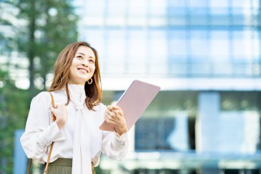 Açık havada tablet bilgisayar kullanan günlük kıyafetli bir kadın.