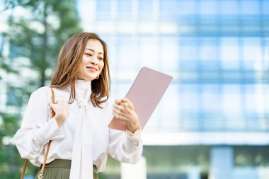 Açık havada tablet bilgisayar kullanan günlük kıyafetli bir kadın.