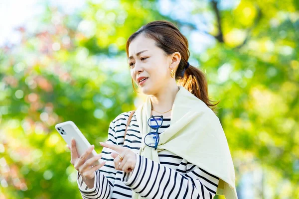 Açık Havada Sorunlu Bir Ifadeyle Akıllı Telefona Bakan Bir Kadın — Stok fotoğraf