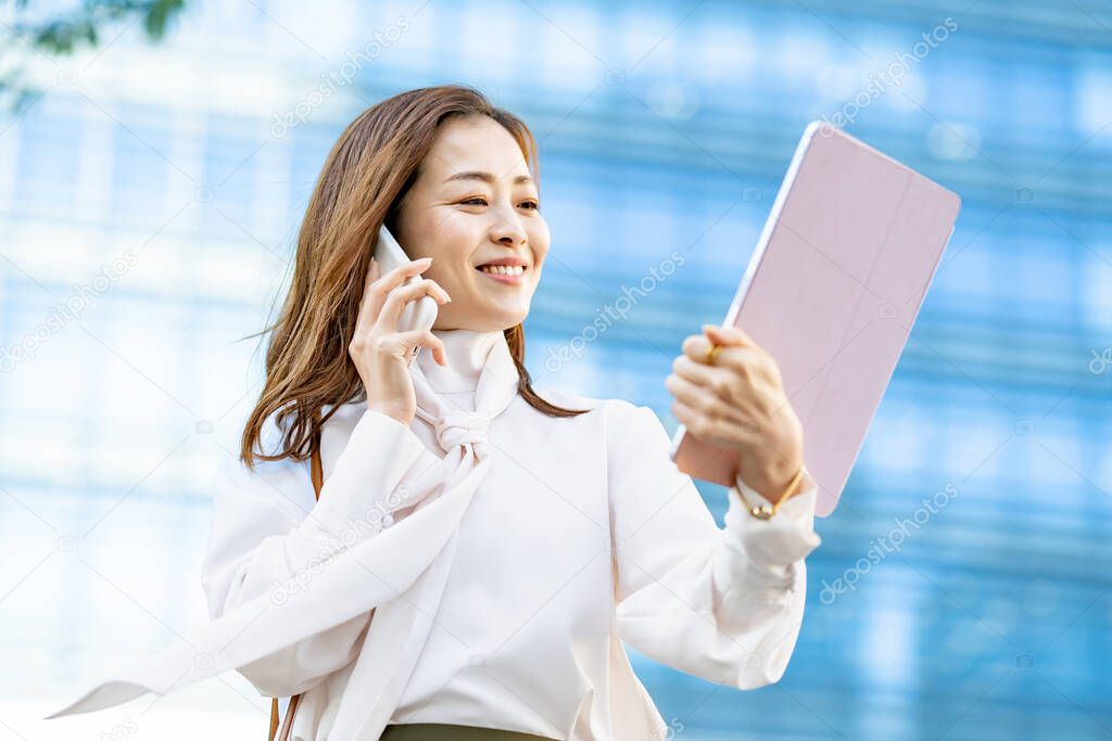 A smiling woman talking on a smartphone outdoors