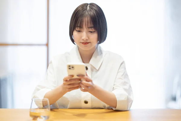 部屋でスマートフォンを操作する女性 — ストック写真