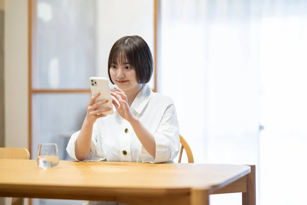 部屋でスマートフォンを操作する女性 — ストック写真