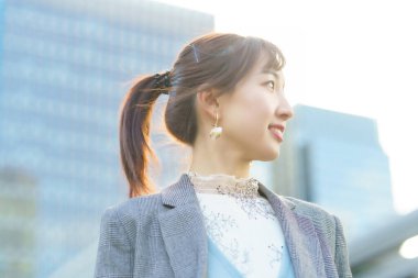 Şehirde gökyüzüne bakan genç bir kadın.