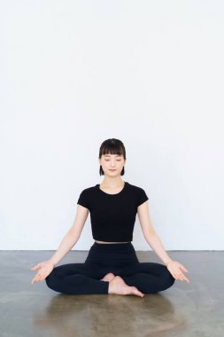 Asyalı genç kadın yoga pozunda mantra meditasyon yapıyor.