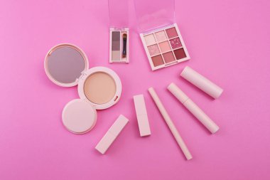 Pembe arkaplana yerleştirilmiş makyaj aletleri.