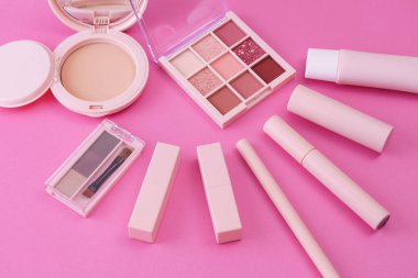 Pembe arkaplana yerleştirilmiş makyaj aletleri.