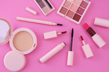 Pembe arkaplana yerleştirilmiş makyaj aletleri.