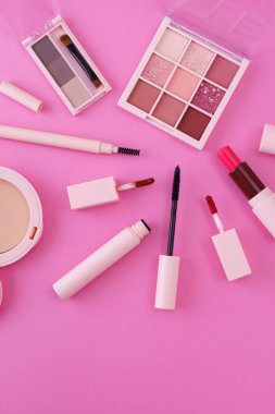 Pembe arkaplana yerleştirilmiş makyaj aletleri.