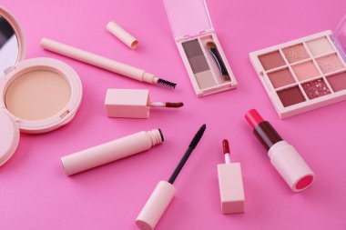 Pembe arkaplana yerleştirilmiş makyaj aletleri.