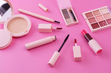 Pembe arkaplana yerleştirilmiş makyaj aletleri.
