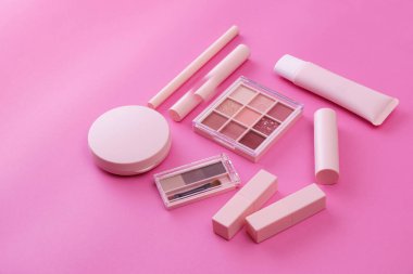 Pembe arkaplana yerleştirilmiş makyaj aletleri.