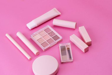 Pembe arkaplana yerleştirilmiş makyaj aletleri.