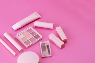 Pembe arkaplana yerleştirilmiş makyaj aletleri.