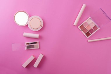 Makyaj aletleri ve pembe bir arka plan.