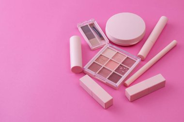 Pembe arkaplana yerleştirilmiş makyaj aletleri.