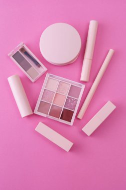 Pembe arkaplana yerleştirilmiş makyaj aletleri.