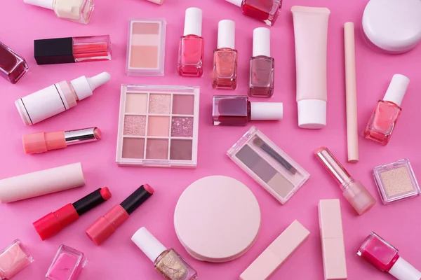 Pembe arkaplana yerleştirilmiş makyaj aletleri.