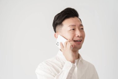 Beyaz gömlekli bir adam akıllı telefondan konuşuyor.