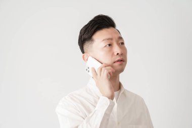 Beyaz gömlekli bir adam akıllı telefondan konuşuyor.