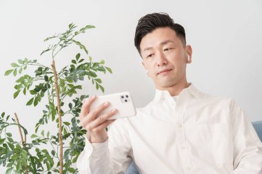 İçerideki akıllı telefon ekranına bakan bir adam.