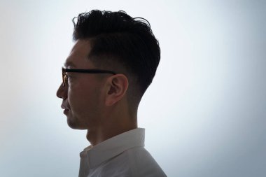 Ciddi yüzlü, gözlüklü Asyalı bir adam.