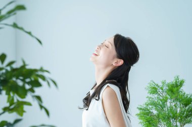 Pencerenin yanındaki ışıkta yıkanan bir kadın derin bir nefes alıyor.