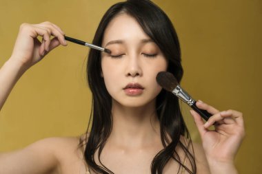 Parlak makyajlı ve altın sarısı olan bir kadın.