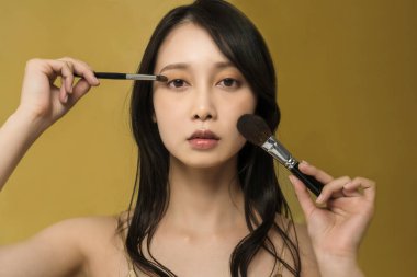 Parlak makyajlı ve altın sarısı olan bir kadın.