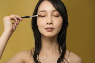 Parlak makyajlı ve altın sarısı olan bir kadın.