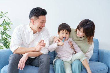 Ebeveynler ve çocuklar koltukta dişlerini fırçalıyorlar.