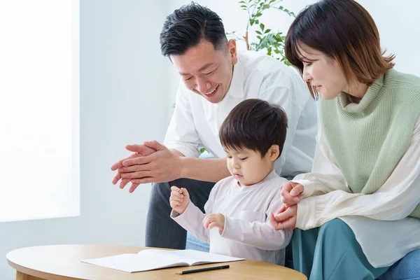 Kalemle çizim yapan bir çocuk ve ailesi ona bakıyor.