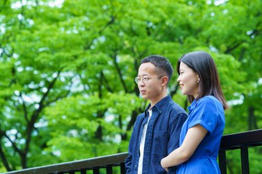 Genç bir çift yeşil bir parkta sohbet ediyor.