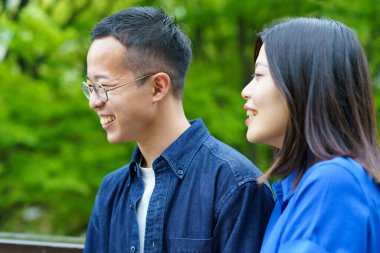 Genç bir çift yeşil bir parkta sohbet ediyor.