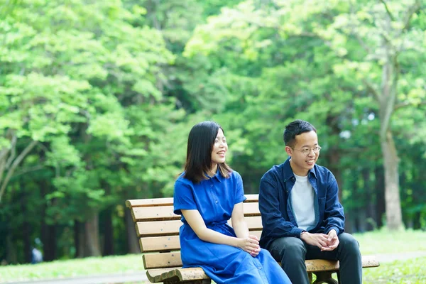 緑の公園のベンチでおしゃべりしている若いカップル — ストック写真
