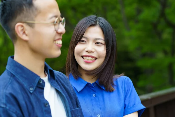 Genç bir çift yeşil bir parkta sohbet ediyor.