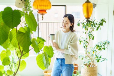 Bitkilerle çevrili Asyalı bir kadın dinleniyor.
