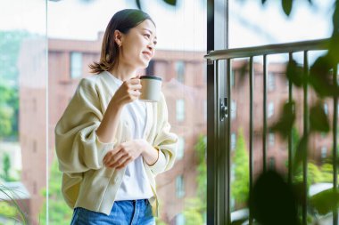 Bitkilerle çevrili Asyalı bir kadın dinleniyor.