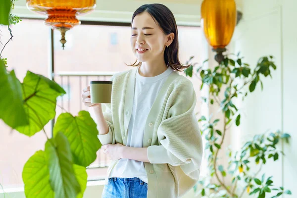 Bitkilerle çevrili Asyalı bir kadın dinleniyor.