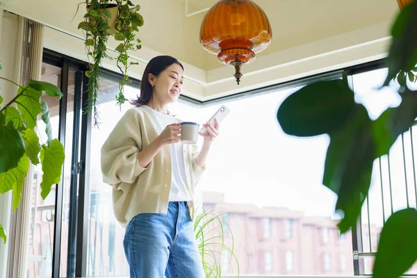 Odadaki akıllı telefonun ekranına bakan kadın.