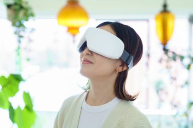 Odada VR gözlüklü bir kadın var.