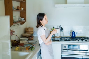 A woman relaxing in the kitchen while cooking